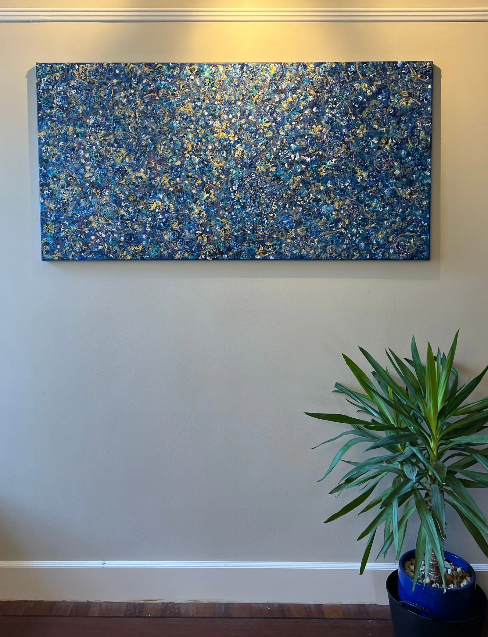 Beginning displayed unframed on a wall above a green plant.
