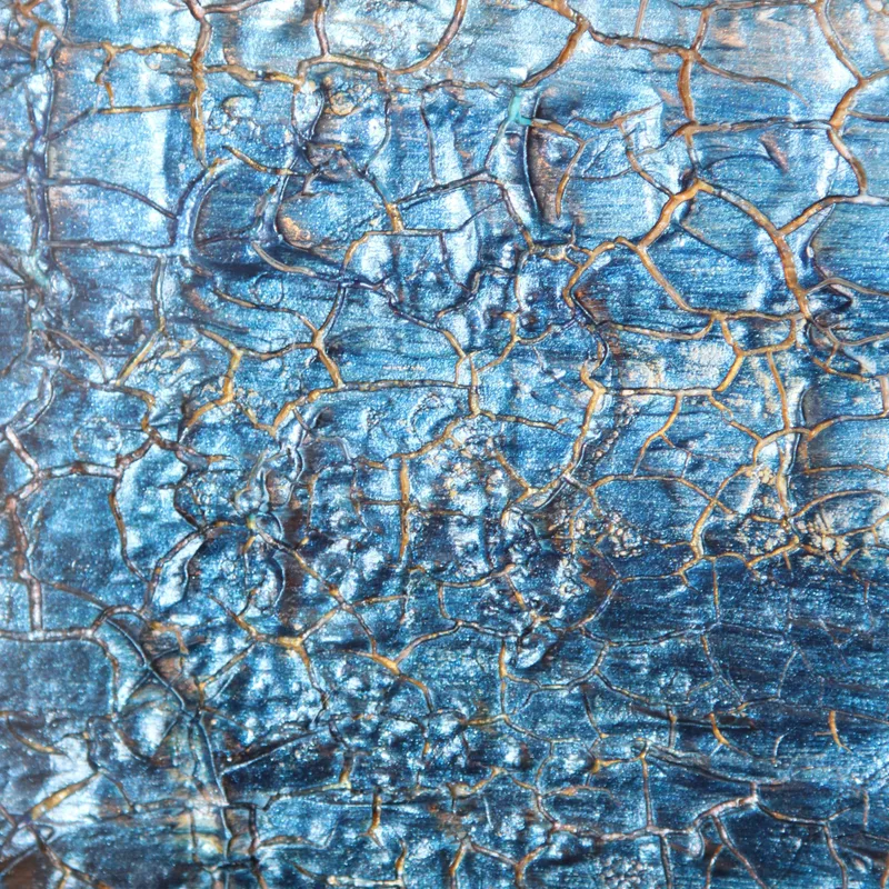 A close-up of crackled metallic blue artwork with gold lines.