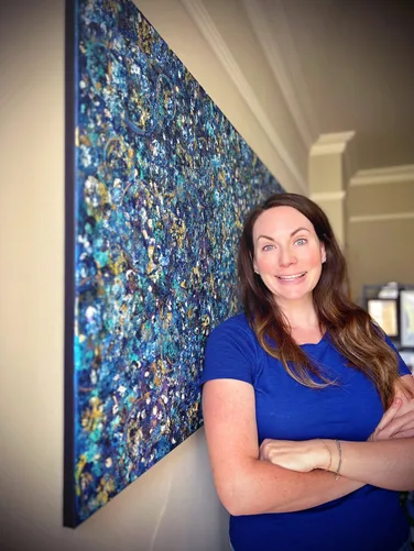 Kelly beside a blue abstract artwork.