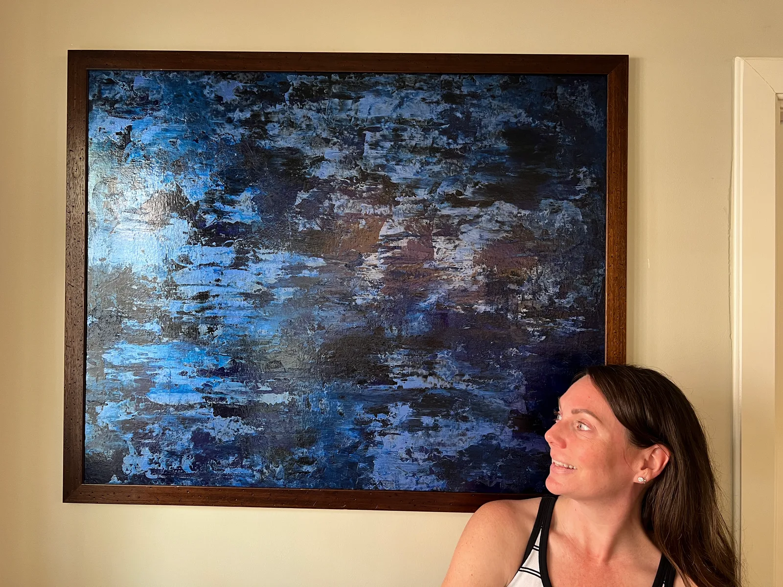 Undercurrent hanging in its brown frame beside a seated woman.